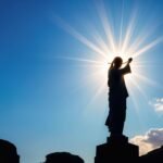 La statue du Christ se dresse en silhouette, illuminée par les rayons du soleil couchant. citation jésus courte